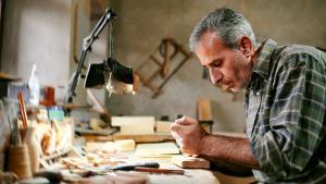 craftsman restores wooden dolls in his garage 50 year old man works with his hands with a table lamp t20 lLmg0k
